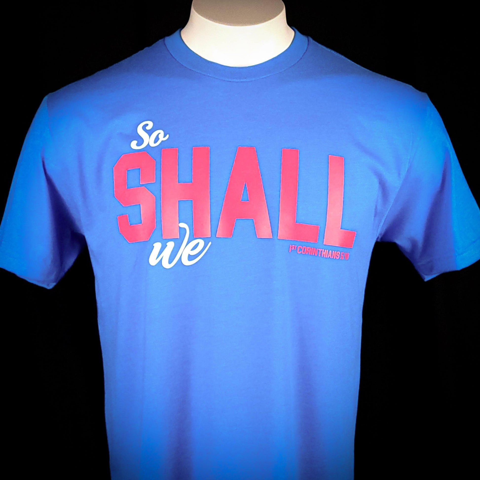 Teal blue shirt with the words So shall we across the front. The verse mentioned with 1 Corinthians