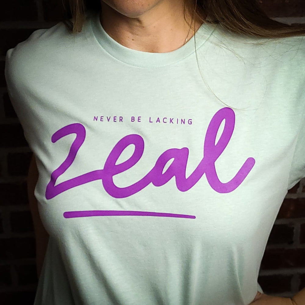 Lite Teal t-shirt that has the words, Never be Lacking Zeal across the chest of the Shirt.