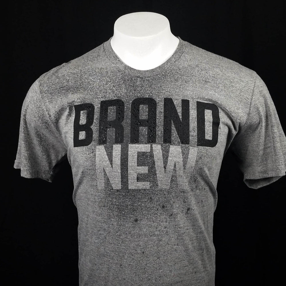 Gray t-shirt with the word brand across the front that reveals the word New when it gets wet.