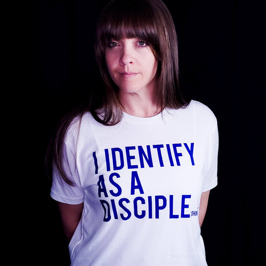 White shirt with blue writing saying I identify as a Disciple.