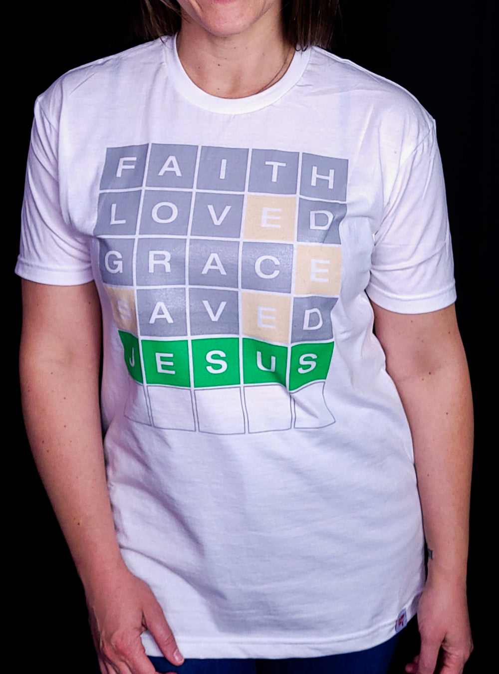 White T-shirt with the words Faith, Loved, Grace, Saved, and Jesus in a format of the game Wordle.