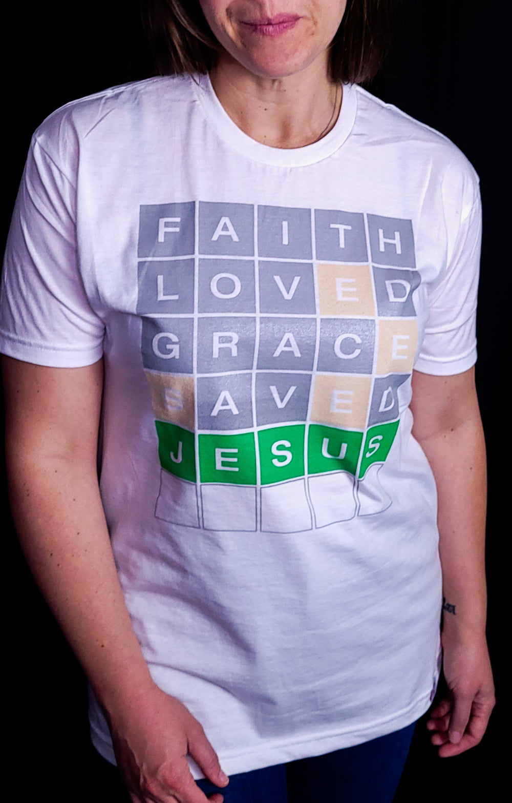 White T-shirt with the words Faith, Loved, Grace, Saved, and Jesus in a format of the game Wordle.