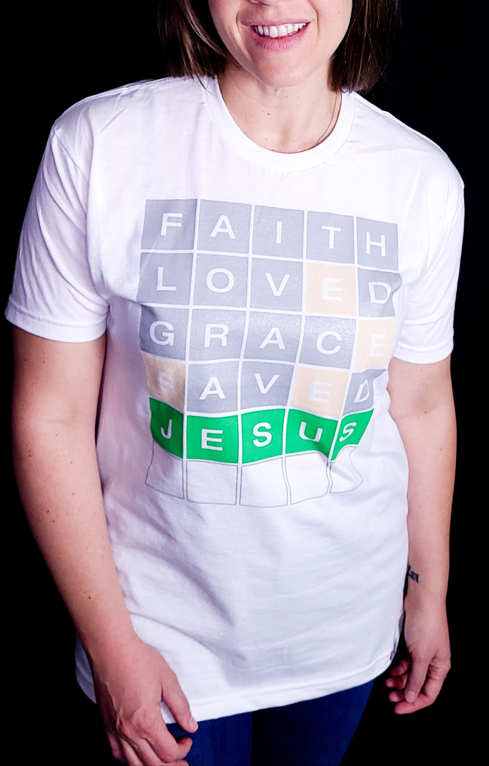 White T-shirt with the words Faith, Loved, Grace, Saved, and Jesus in a format of the game Wordle.