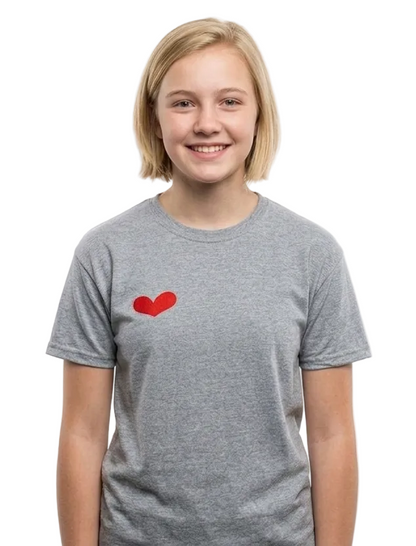 A smiling young woman with blonde hair wearing a heather gray crewneck t-shirt with a small red heart on the left chest, photographed against a solid white background.