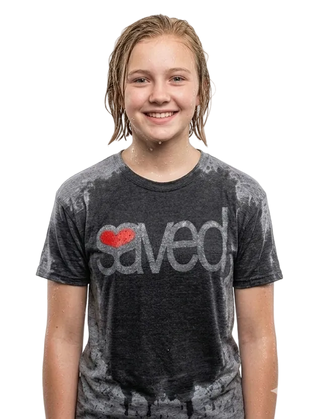 A smiling young woman with wet hair wearing a dark gray mineral-wash t-shirt with a red heart and the word 'saved' printed on the front, set against a plain white background.