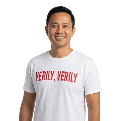 Man wearing a white t-shirt with 'VERILY, VERILY' text on a plain background