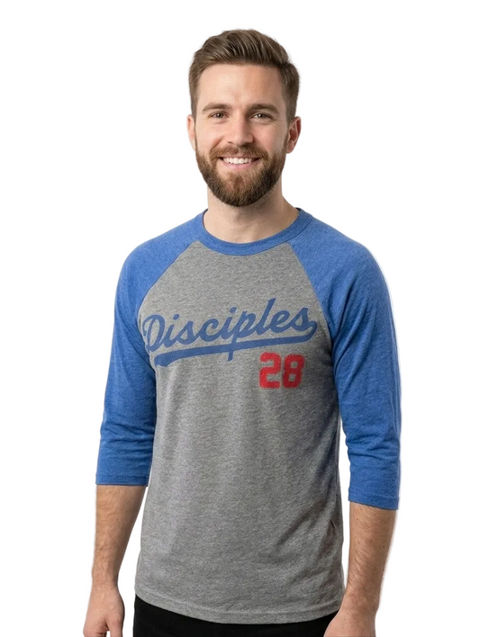 A smiling man with a beard wearing a heather gray and blue raglan baseball t-shirt with 'Disciples 28' printed on the front, set against a plain light gray background.