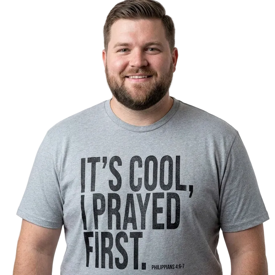 A smiling man with a beard wearing a heather gray t-shirt with the black printed text 'IT'S COOL, I PRAYED FIRST. PHILIPPIANS 4:6-7' on the front, set against a plain white background.