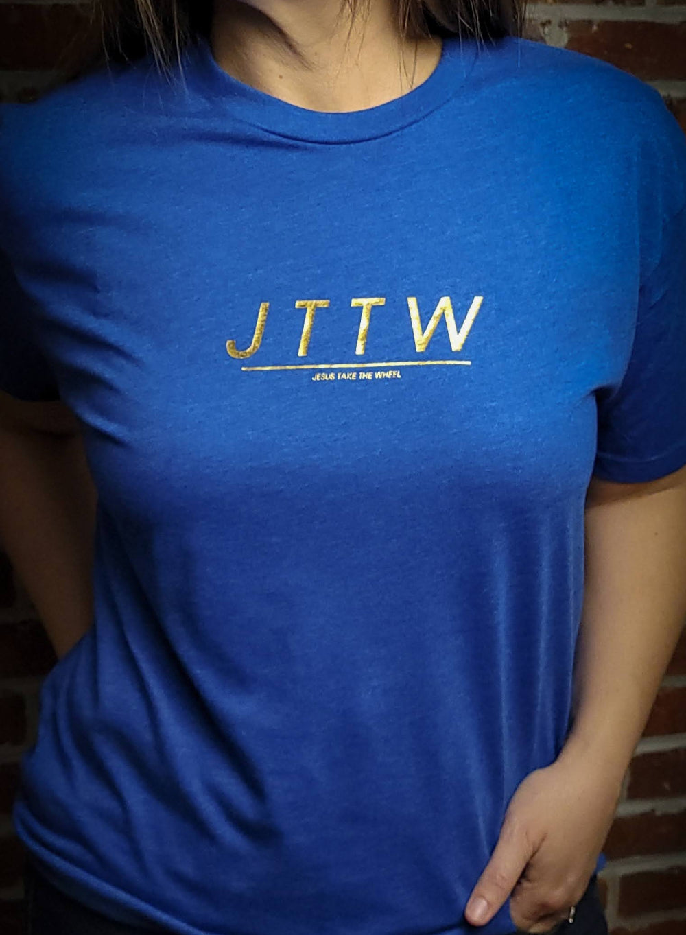 Blue shirt with gold letters spelling out JTTW. Jesus Take The Wheel