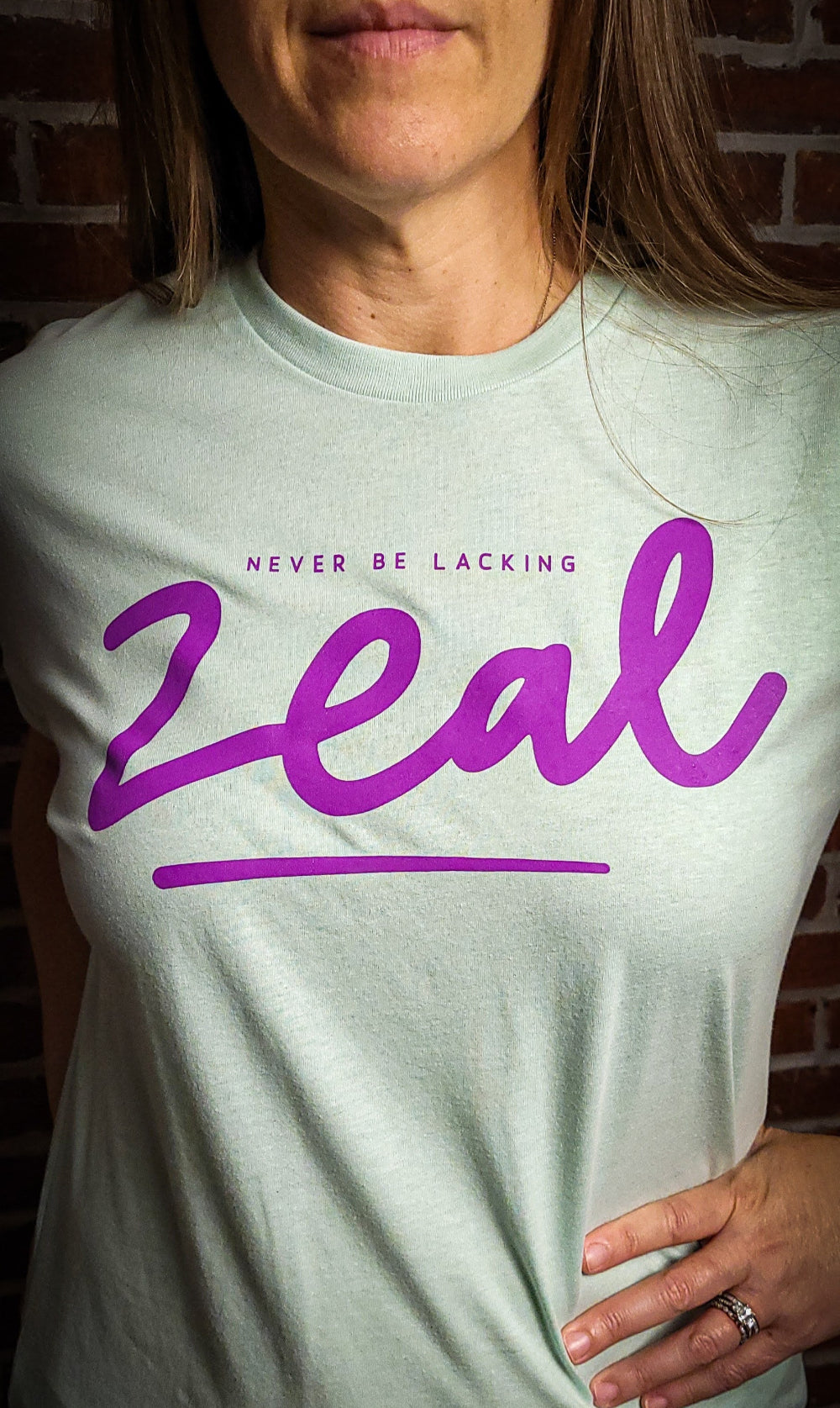 Lite Teal t-shirt that has the words, Never be Lacking Zeal across the chest of the Shirt. 