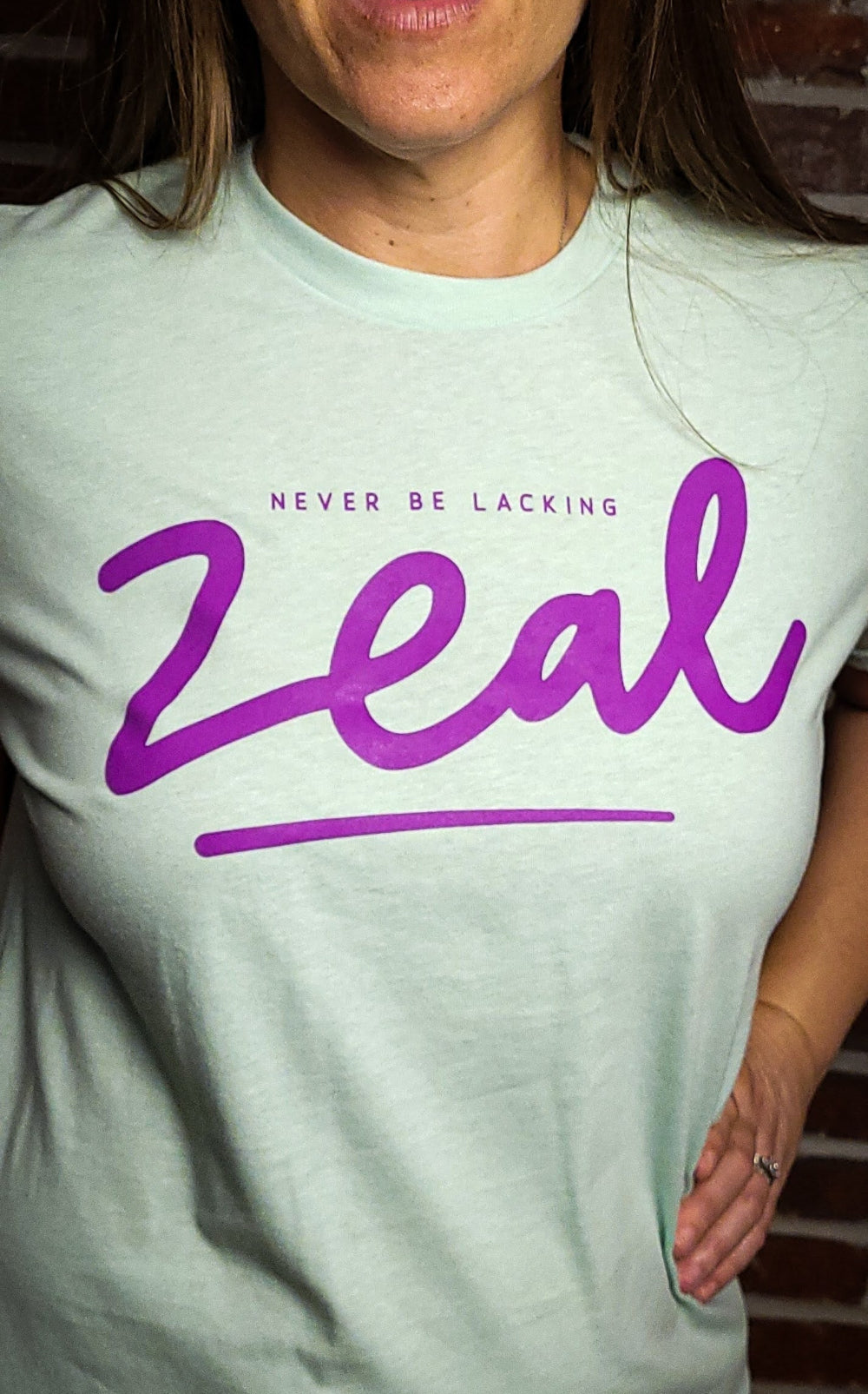 Lite Teal t-shirt that has the words, Never be Lacking Zeal across the chest of the Shirt. 